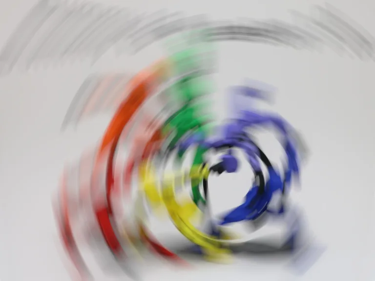 Rozmazaný vícebarevný kruhový symbol na světle šedém pozadí