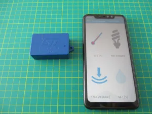 Modrá vývojová deska SensorTile.box vedle telefonu s aplikací pro zobrazení údajů ze senzorů