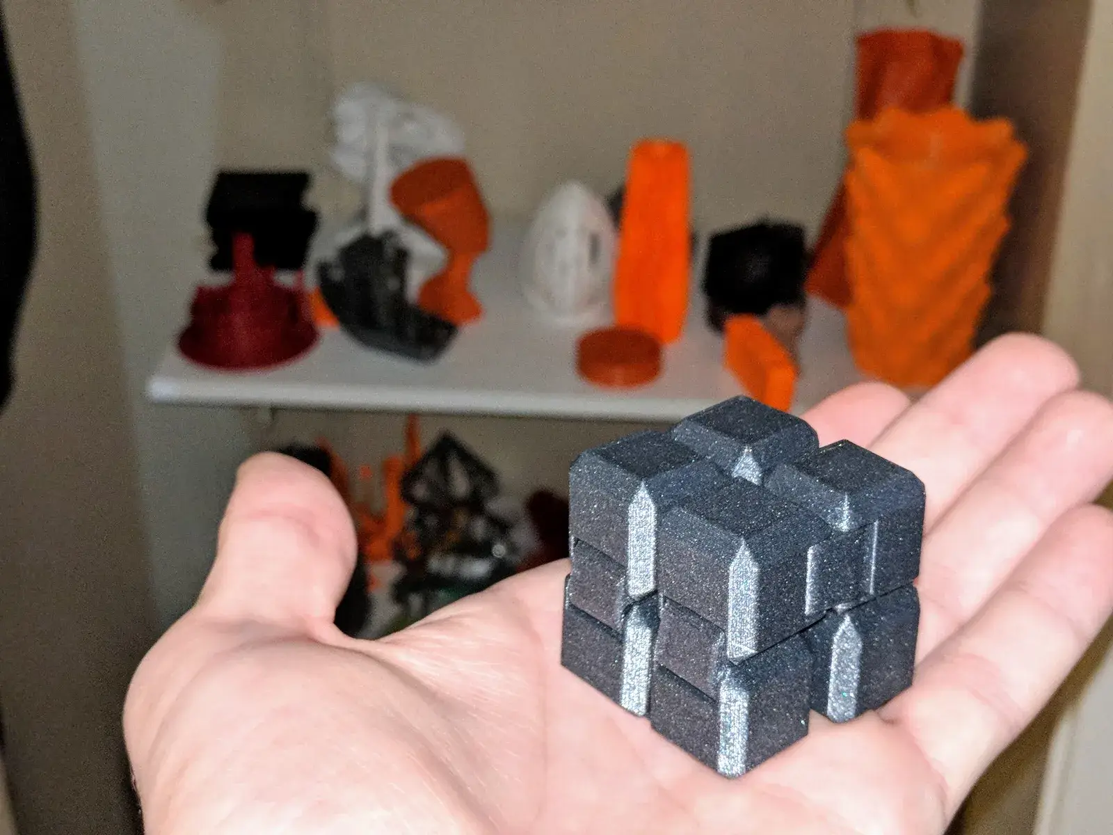 Černá 3D tištěná nekonečná kostka s pohyblivými články na dlani