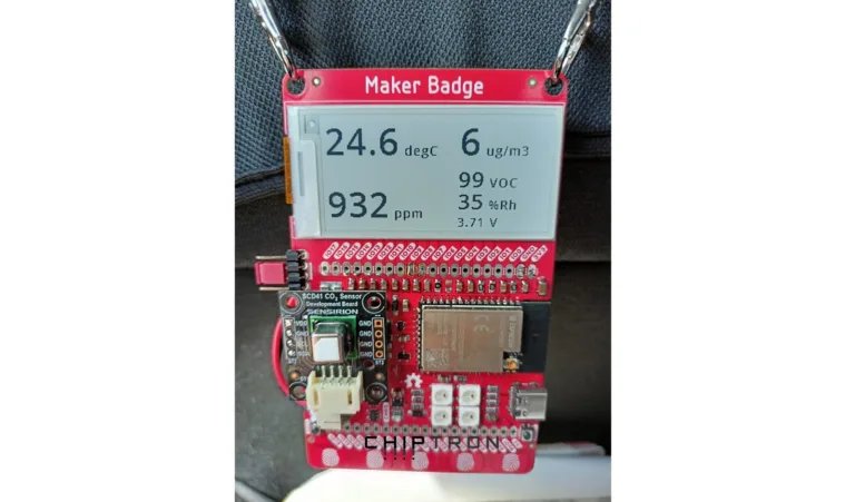 Červený Maker Badge s displejem zobrazujícím teplotu a další údaje v autě