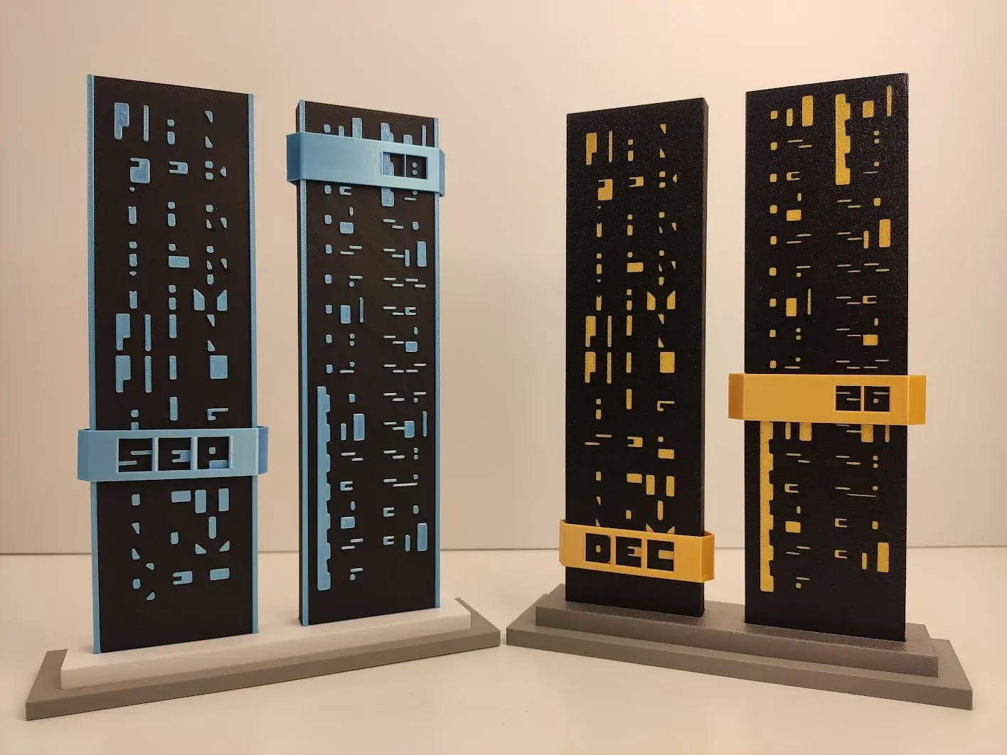 Čtyři varianty černého 3D tištěného monolitického kalendáře s barevnými posuvníky