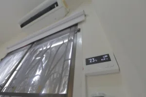 Nástěnná klimatizace s digitálním displejem vedle okna
