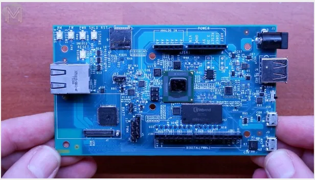 Modrá elektronická deska s množstvím konektorů držená v rukou