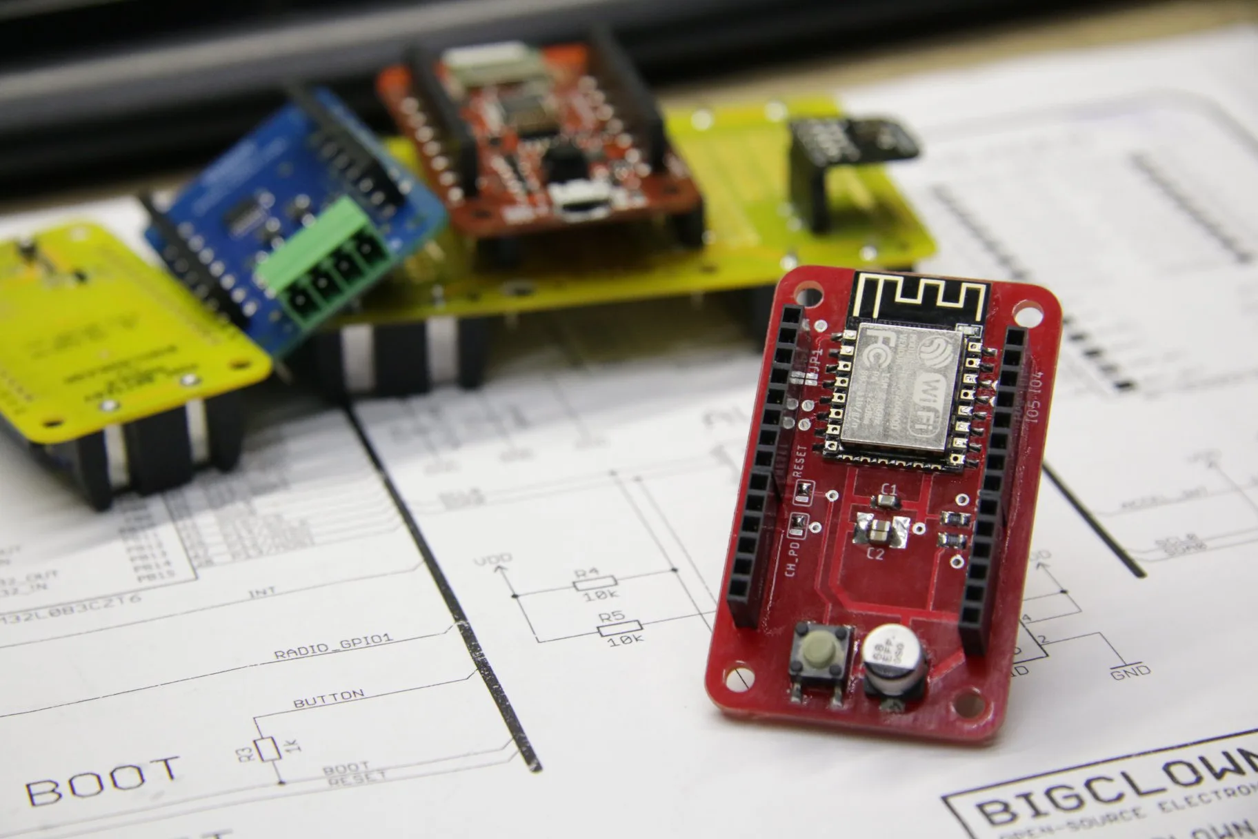 Červený WiFi modul BigClown s ESP8266 vedle dalších vývojových desek