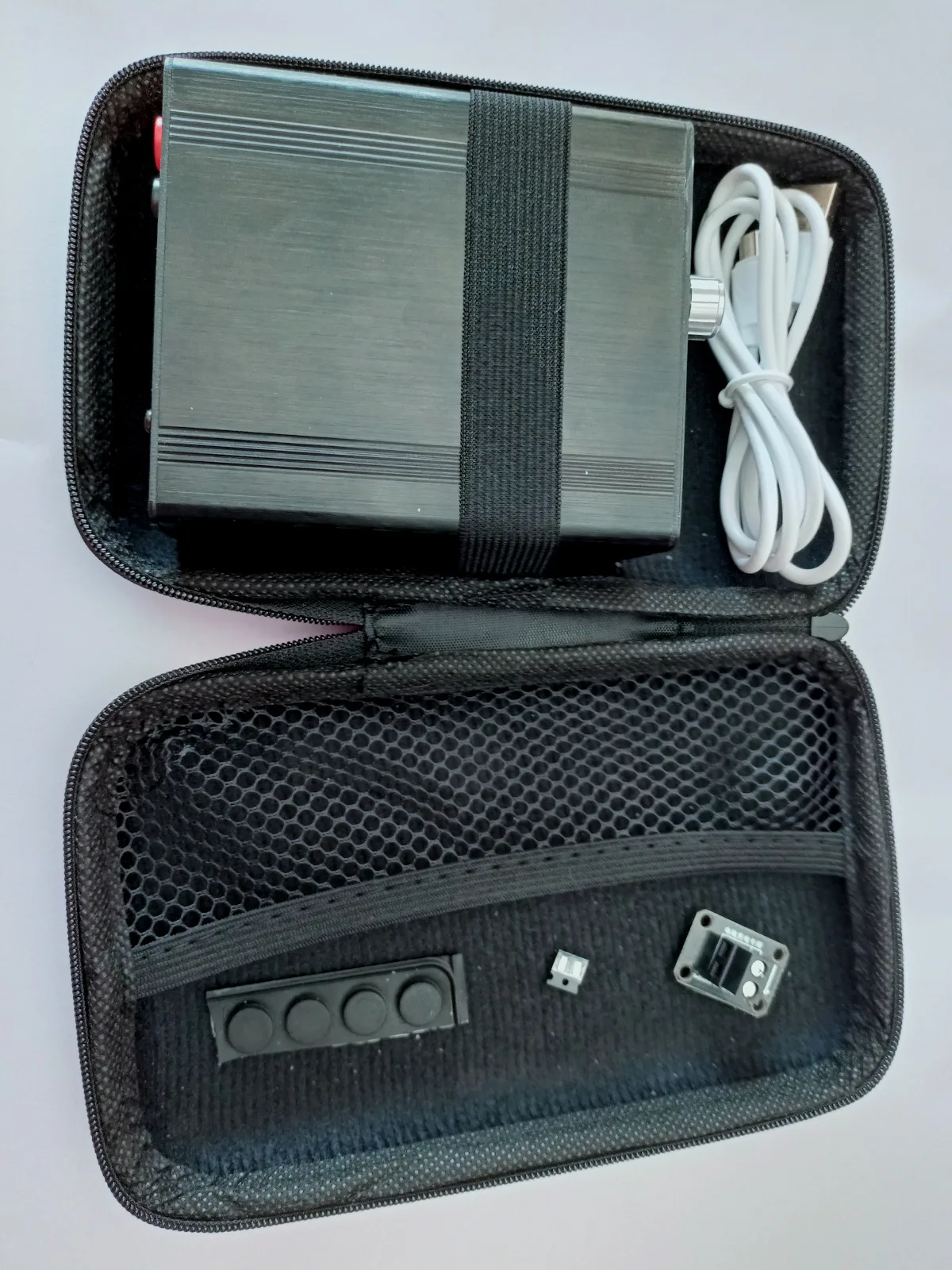 Obsah balení DC6006L: regulovatelný zdroj, USB kabel a gumové nožičky
