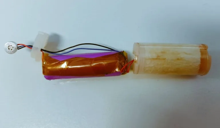 Rozebraná jednorázová elektronická cigareta s baterií, vodiči a průhledným tělem