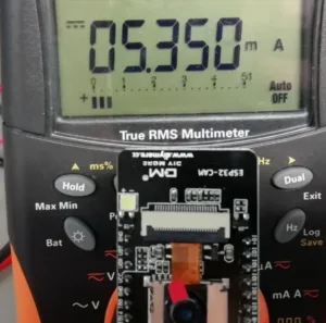 Modul ESP32-CAM s kamerou OV2640 položený na multimetru ukazujícím 0,350 mA