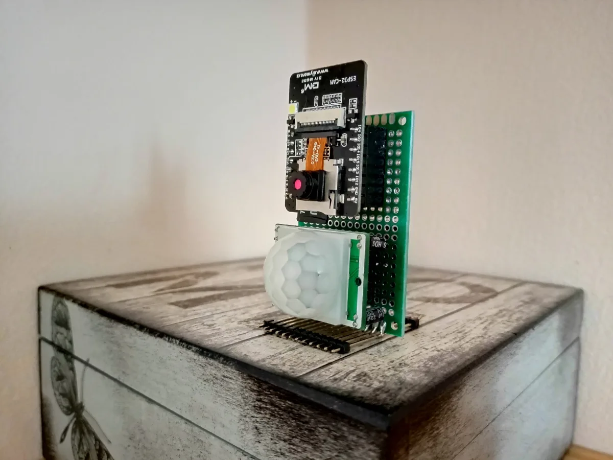 Deska ESP32-CAM s připojeným PIR senzorem na dřevěné krabičce