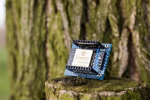 Modrá vývojová deska ESP32 MiniKit s kovovým stíněním na pařezu