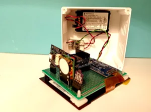 Rozebraný domácí monitor CO₂ s deskou ESP32, čidly a displejem ePaper
