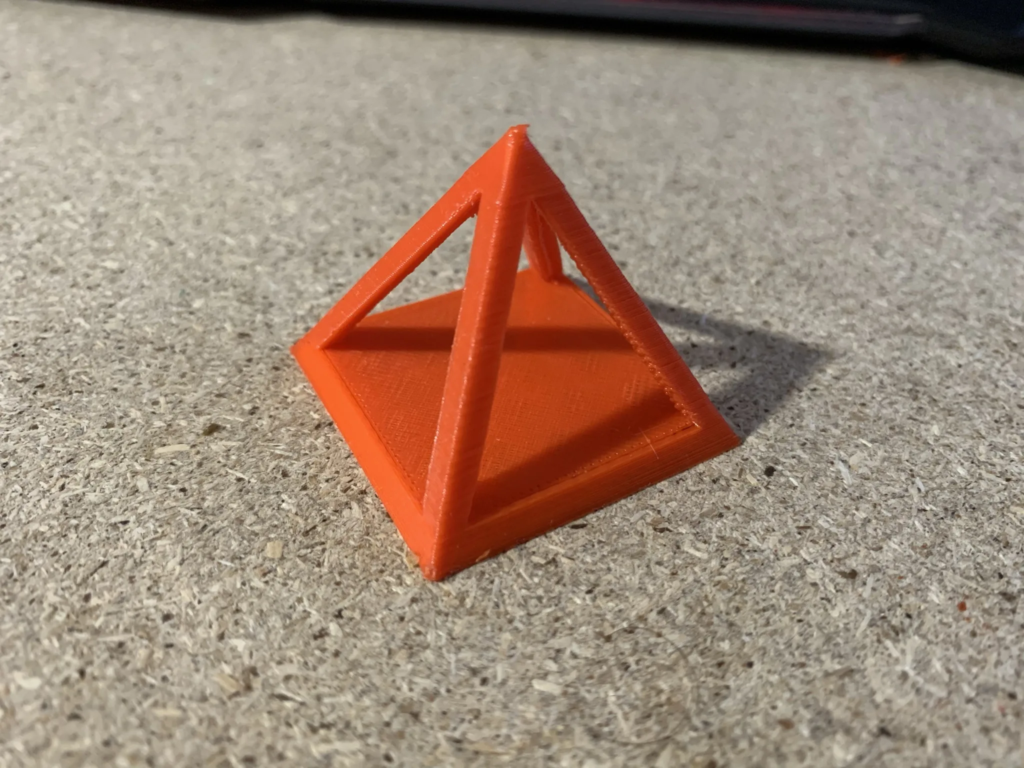 Oranžový 3D vytištěný pyramidový model na podlaze