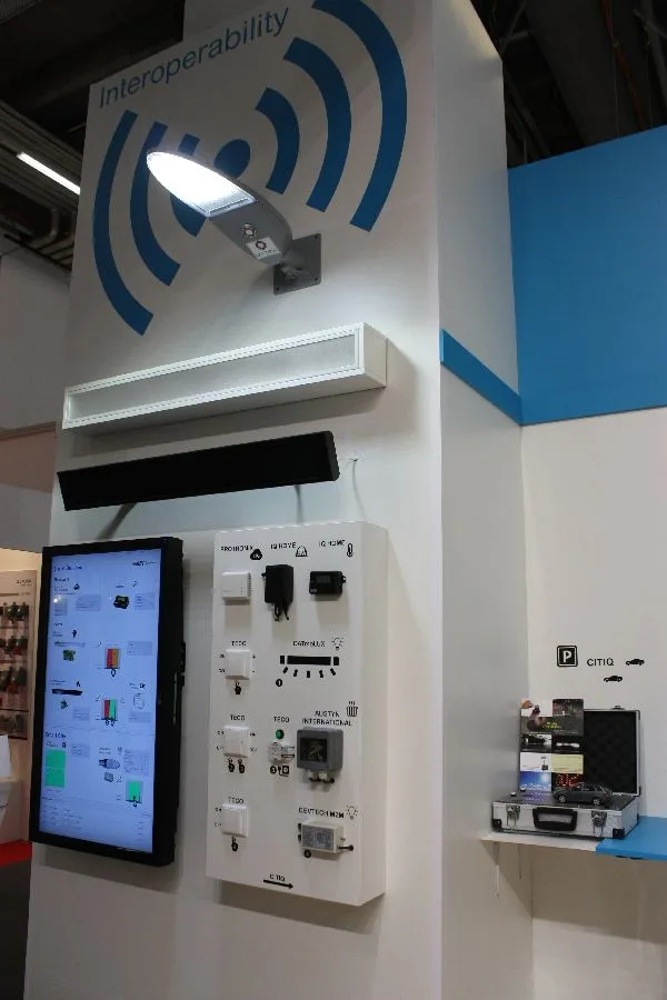 Výstavní stánek s bezdrátovými zařízeními, ovládacím panelem a nápisem Interoperability