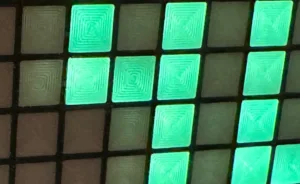 Mřížka svítících tyrkysových a tmavých čtvercových dlaždic projektu Lazy Mini Grid
