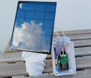 Venkovní meteostanice se solárním panelem a odkrytou elektronickou deskou v krytu