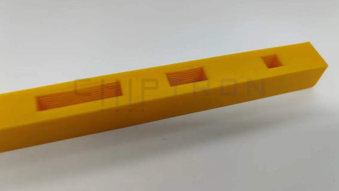 Jantarově žlutý 3D tištěný hranol s otvory pro testování přemostění