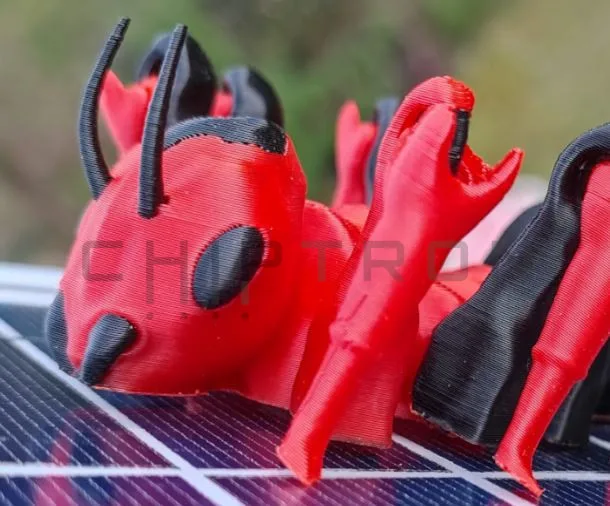 Červený a černý 3D tištěný mravenec stojí na podložce tiskárny