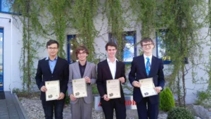 Čtyři studenti drží diplomy před budovou