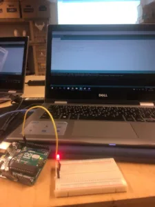 Vývojová deska Arduino s breadboardem a vodiči vedle notebooku