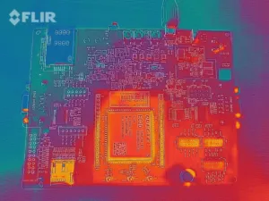 Termální snímek elektronické desky s teplejšími součástkami zvýrazněnými oranžově a červeně