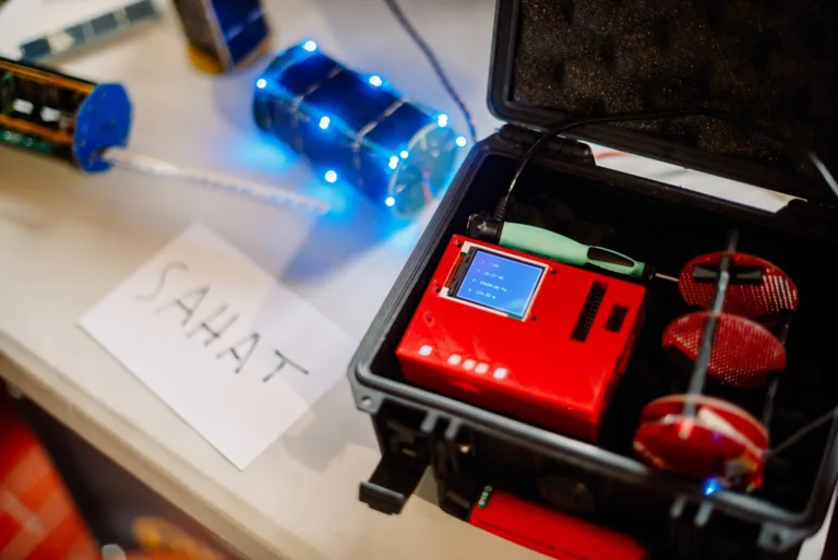 Otevřená černá krabička s červeným elektronickým zařízením a malým displejem