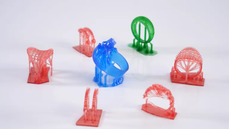 Barevné 3D tištěné testovací modely rozmístěné na podložce