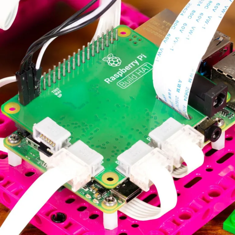 Zelená deska Raspberry Pi Build HAT s připojenými kabely na růžové základně LEGO