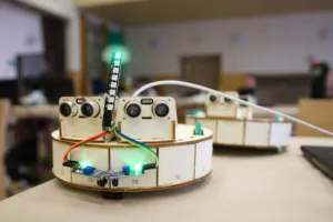Robotická stavebnice na stole s ultrazvukovými senzory, kabely a svítící LED