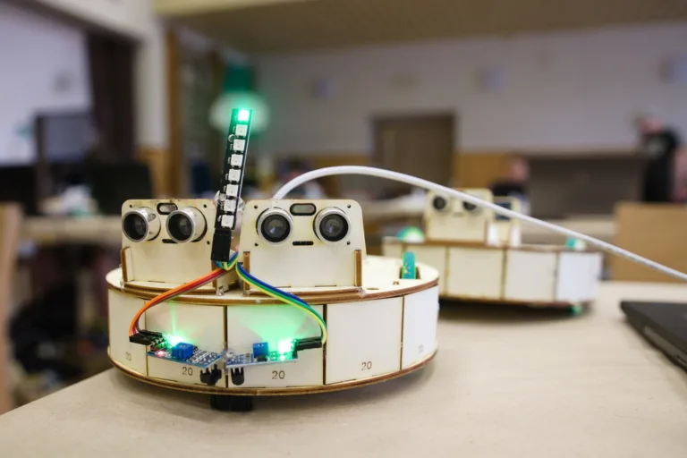 Robotická stavebnice na stole s ultrazvukovými senzory, kabely a svítící LED