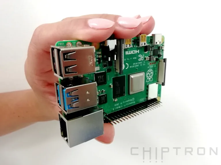 Raspberry Pi 4B držená v ruce, s USB porty a odkrytou čtečkou microSD