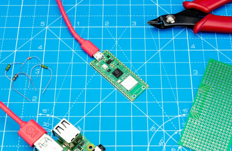 Deska Raspberry Pi Pico W na modré řezací podložce vedle kleští a dalších součástek