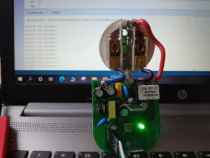Rozebraná zásuvka Sonoff S20 s deskou ESP8266 a vodiči před monitorem