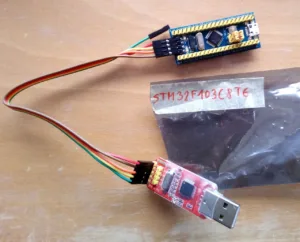 Dvě STM32 vývojové desky propojené barevnými vodiči na pracovní podložce